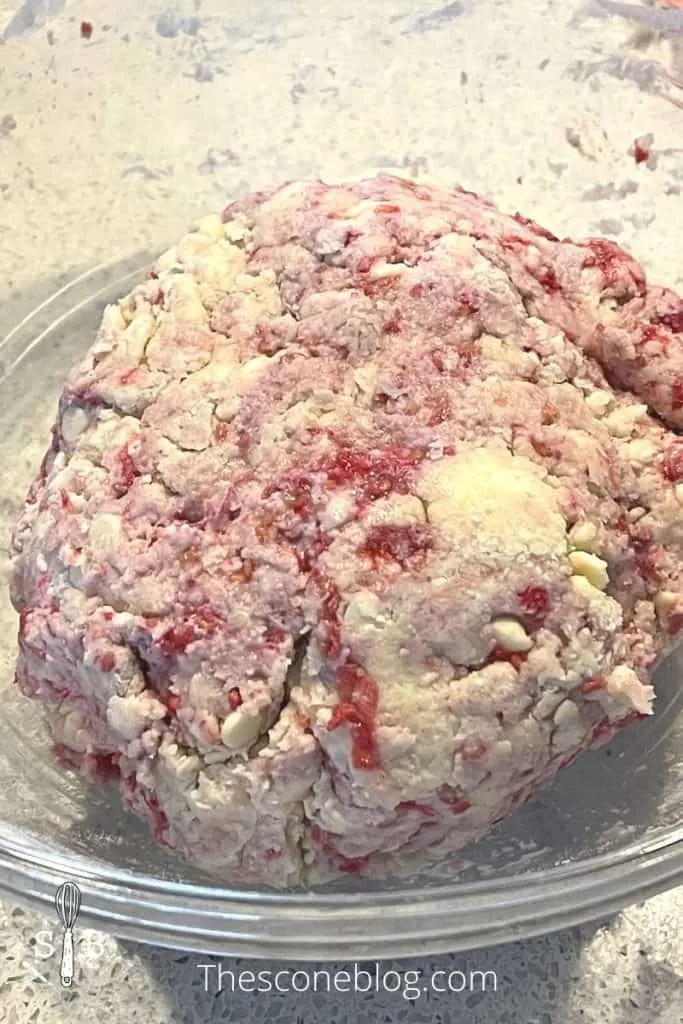 Cold ingredients with raspberries and white chocolate mixed into a dough ball